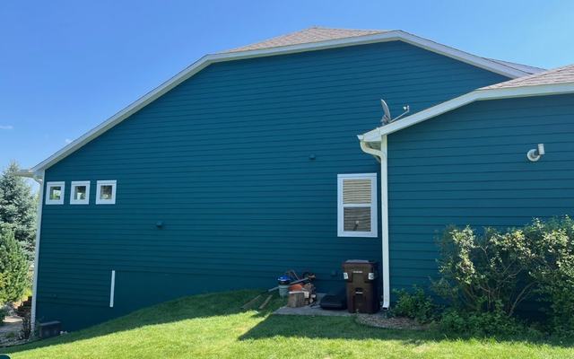 Teal-green gable end with crisp white trim after exterior painting