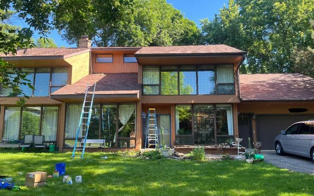 Ladders and drop cloths set up against a house before exterior painting begins